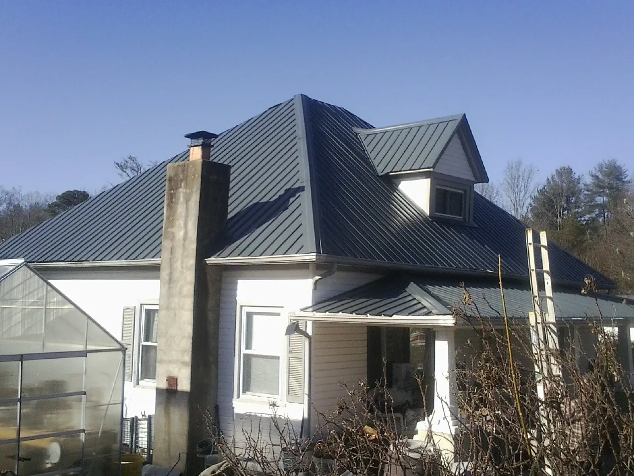 Dark blue standing seam metal roof on a white farmhouse with dormer — Slate & Tile Roof Repair by Roofing Brothers in Port Penn
