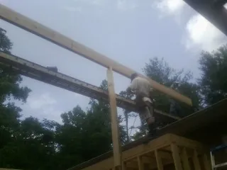 Carpenter setting a ridge beam over a new addition frame — Ice Dam Removal by Roofing Brothers in Port Penn