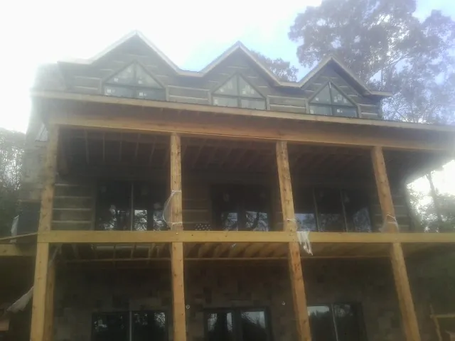 Dormers and porch framing on a large log home under construction — Roof Coating work by our crew in Port Penn