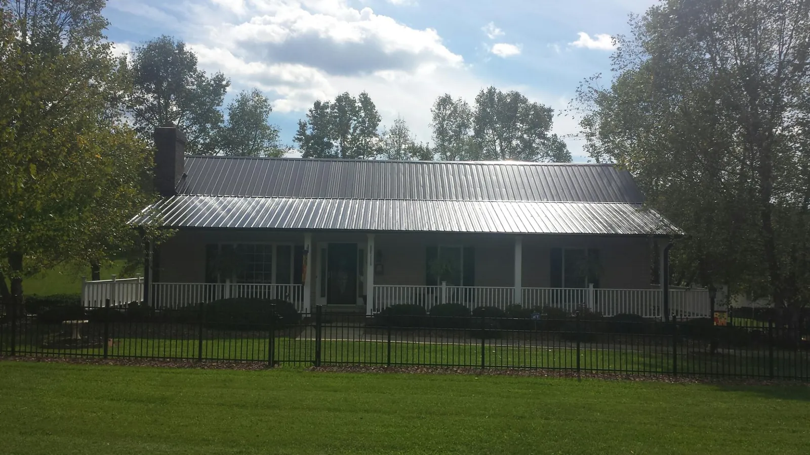 Gray metal roof on a brick ranch with a full width front porch — Gutter Guard Installation work by our crew in Port Penn