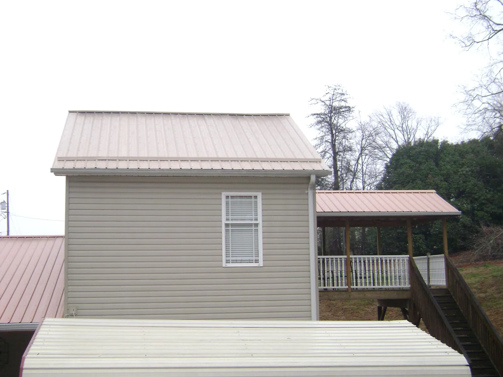 Tan metal roofs on a two story addition and attached porch, from a Roof Replacement job in Port Penn