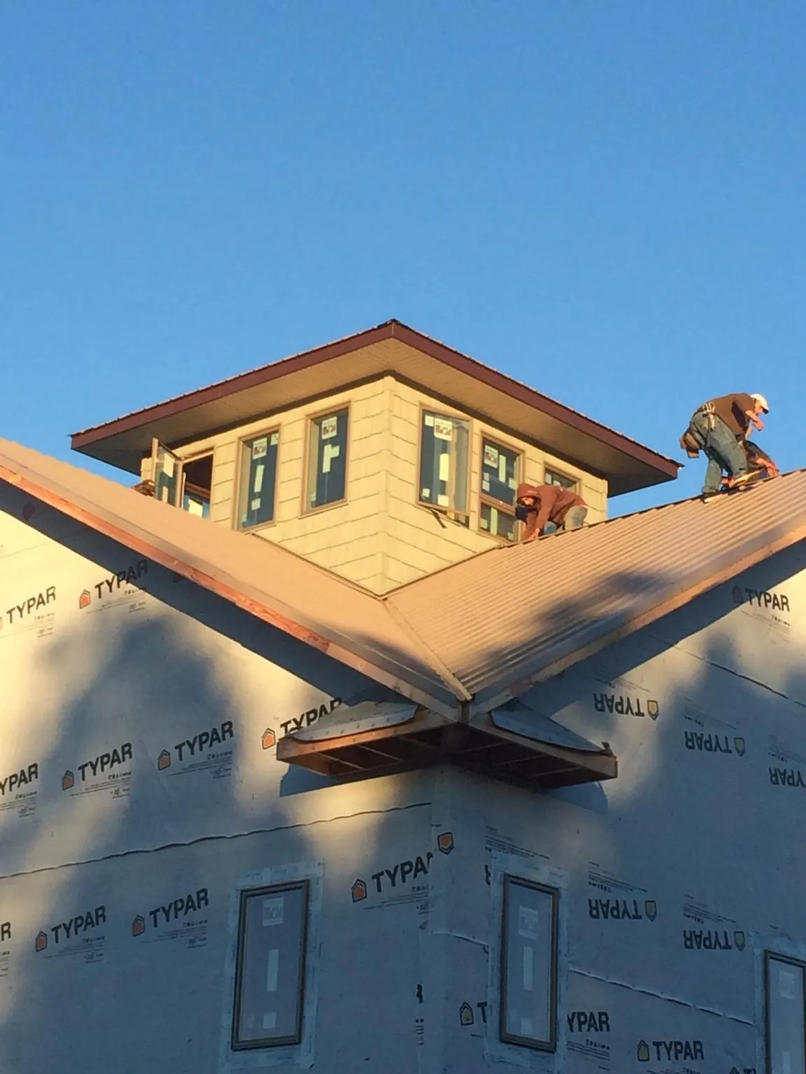 Roofers working around a rooftop cupola on a new metal roof at sunset — Roof Waterproofing in Port Penn by Roofing Brothers